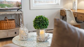 A cozy living room with a round coffee table, a potted plant, and a lit candle. - Chic Garden Suite (Victoria)