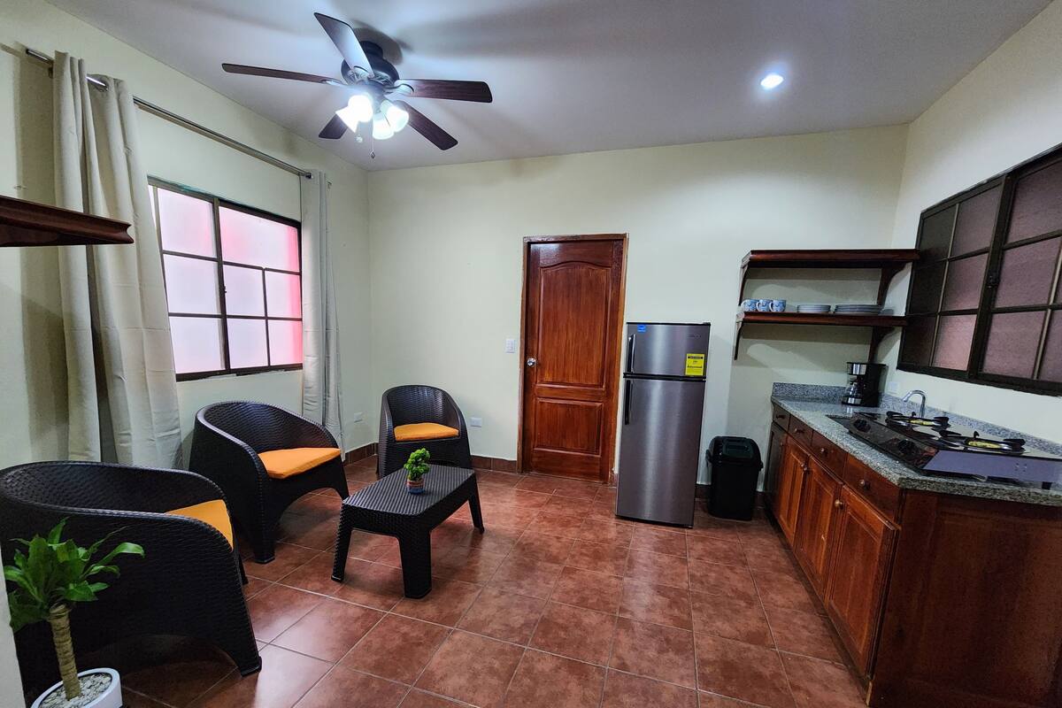 A compact kitchen with a refrigerator, stove, and a ceiling fan.