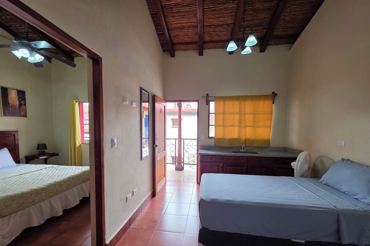 A hotel room with two beds, a bathroom with a sink, and a balcony with a view.