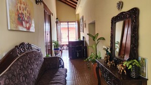 A spacious living area with a patterned sofa, a large mirror, and decorative plants. - Casona Macondo (Granada)