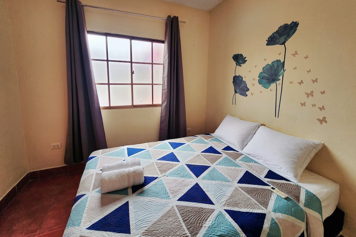 A bedroom with a bed, curtains, a window, and wall decorations.