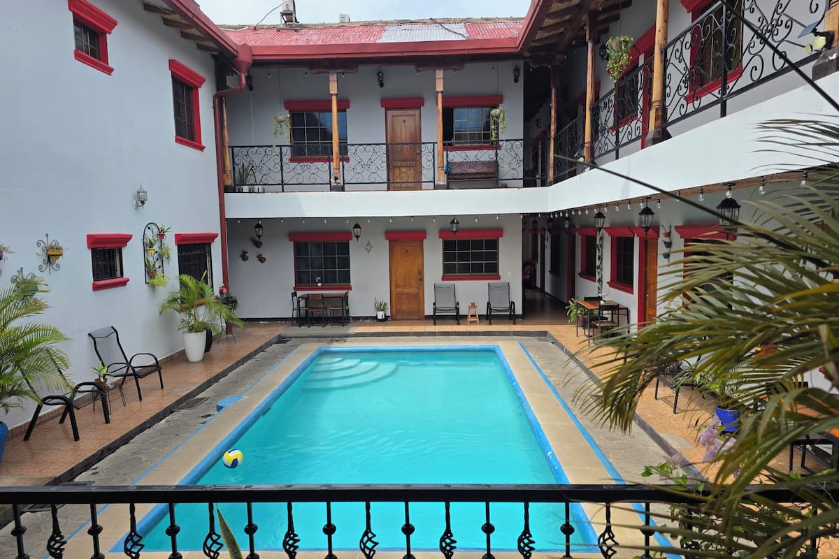 A courtyard with a swimming pool, outdoor seating, and a two-story building with balconies.