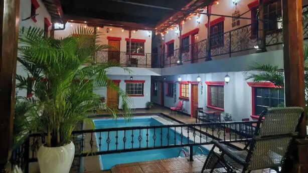 A multi-level building with a central courtyard, a pool, and outdoor seating areas. - Casona Macondo (Granada)