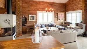 Interior acogedor de una cabaña de troncos con chimenea, una araña y una zona de estar confortable.