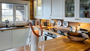 Una cocina con armarios blancos, encimera de madera y un gran florero de vidrio con una vela.