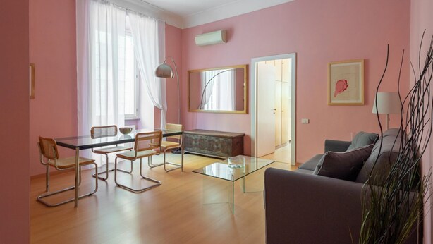 A room with a dining table, chairs, a sofa, a cabinet, and a mirror.