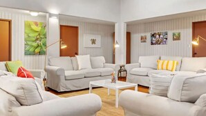 Een ruime woonkamer met witte banken, een bijzettafeltje en kunstwerken aan de muren.