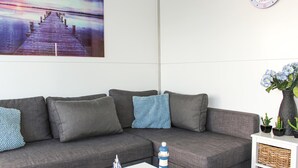 En moderne stue med en grå modulsofa, et lille hvidt sofabord og en dekorativ model af et fyrtårn.