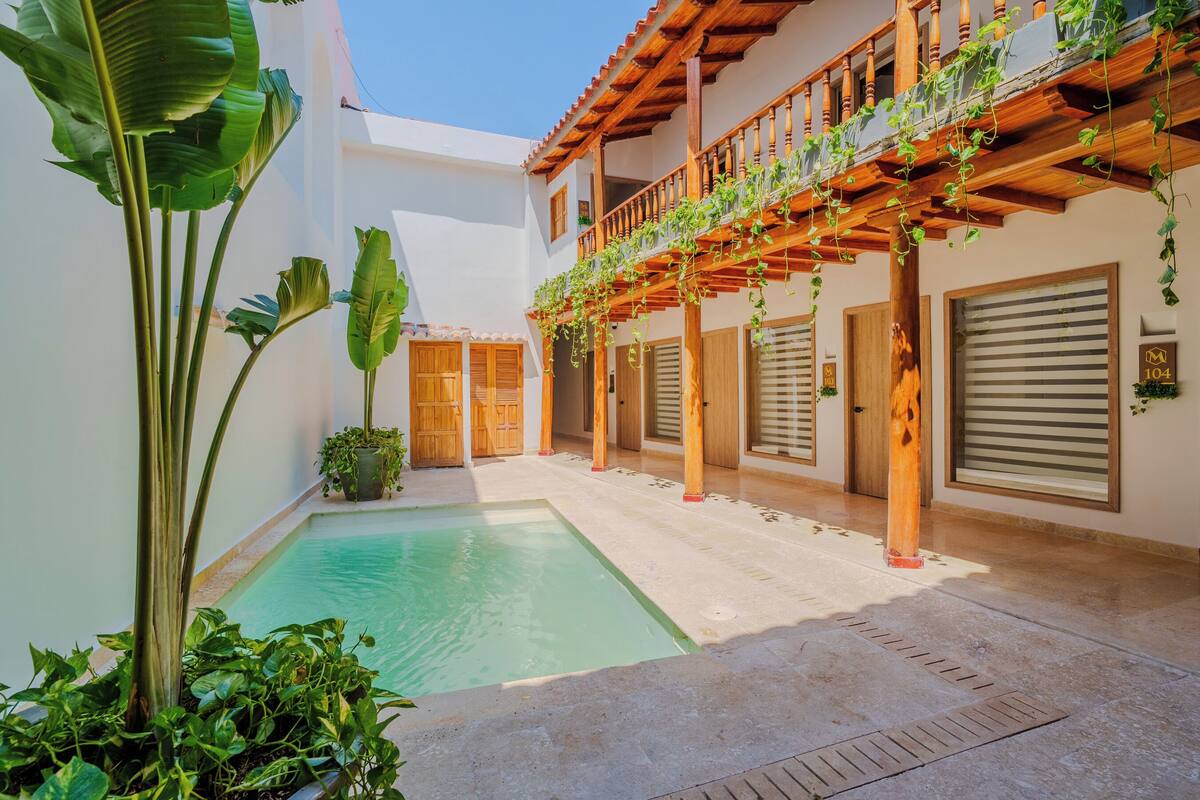 Une cour avec une piscine, des balcons en bois et des plantes en pot.