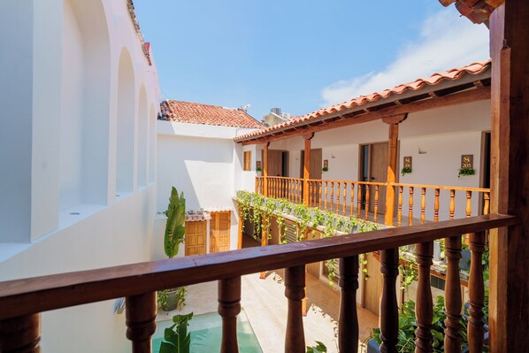 Un patio con balcón de madera, paredes blancas y techos de tejas.