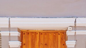 Una puerta de madera con manija metálica, flanqueada por columnas blancas y un pequeño escalón que la precede.