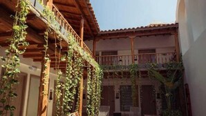 Un patio con piscina, pérgolas de madera y mobiliario exterior.