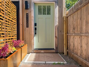 A wooden door with a 'WELCOME' sign, a doormat, and a wooden fence.