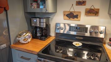 A kitchen with a stainless steel stove, a coffee maker, and wooden fish decorations on the wall.