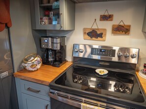 A kitchen with a stainless steel stove, a coffee maker, and wooden fish decorations on the wall.