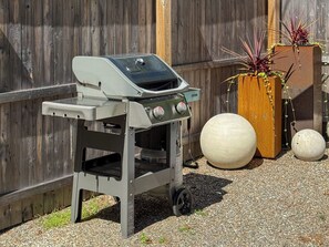 A portable barbecue grill with wheels, a wooden fence, and decorative planters. - Private Forest Retreat • Spa Bath • Near the Coast • Central Midcoast Hub (Searsport)