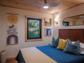 A bedroom with a bed, a window, a ceiling fan, and artwork on the wall. - Private Forest Retreat • Spa Bath • Near the Coast • Central Midcoast Hub (Searsport)