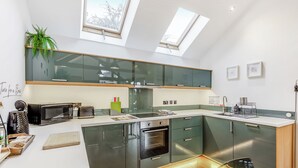 A modern kitchen with skylights, a microwave, a sink, and a dining area. - 1 bedroom accommodation in Llangollen (Llangollen)