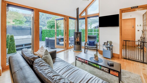 A spacious living area with a large sofa, a fireplace, and a television. - 1 bedroom accommodation in Llangollen (Llangollen)