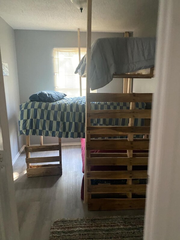 Un dormitorio con dos literas, un edredón a cuadros y una ventana con persianas.