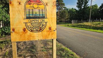 En träskylt med en färgstark symbol och text som visar var campingområdet ligger.