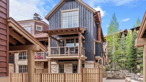 Een meerhoog gebouw met een balkon, stenen details en een houten terras.