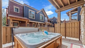 Een jacuzzi in een achtertuin met houten terras en een stenen muur.