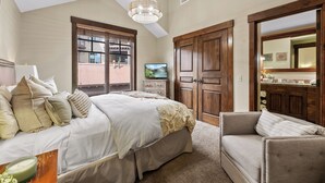Een slaapkamer met een groot bed, een houten garderobe, een televisie en uitzicht op het balkon.