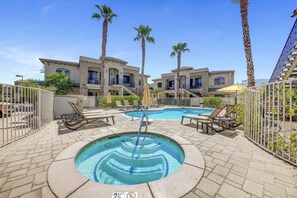A hotel pool area with lounge chairs, a hot tub, and a fenced pool. - Desert Breeze: #244514 1 BR, communal pool! (La Quinta)