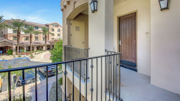 A hotel with a balcony, a parking lot, and a building with a brown door. - Desert Breeze: #244514 1 BR, community pool and spa! (La Quinta)