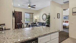 A kitchen with granite countertops, a ceiling fan, and a dining area with a table and chairs. - Desert Breeze: #244514 1 BR, community pool and spa! (La Quinta)