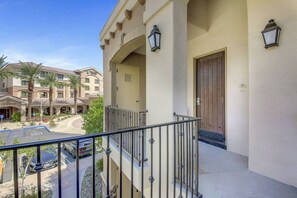 A hotel with a balcony, a parking lot, and a building with a brown door. - Desert Breeze: #244514 1 BR, communal pool! (La Quinta)