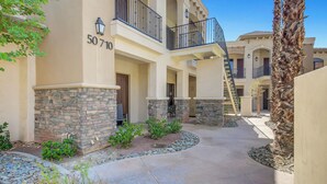 A multi-story building with a stone facade, numbered 50710, featuring balconies and a central courtyard with landscaping. - Desert Breeze: #244514 1 BR, community pool and spa! (La Quinta)