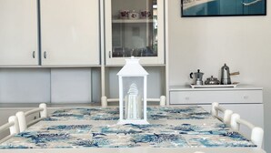 A dining area with a table set for two, a white cabinet with glass doors, and a framed picture on the wall. - M410 - Marcelli, comfortable three-room apartment with large terrace (Marcelli)