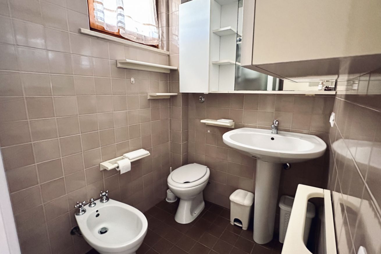 A compact bathroom with a bidet, toilet, sink, and mirror.
