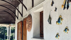 A building with a corrugated metal roof, wooden shutters, and a wall decorated with fish sculptures. - M410 - Marcelli, comfortable three-room apartment with large terrace (Marcelli)
