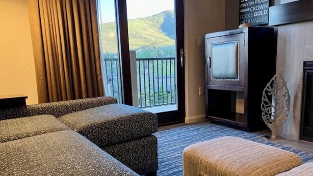A hotel room with a large window, a flat-screen TV, a fireplace, and a view of the hills.