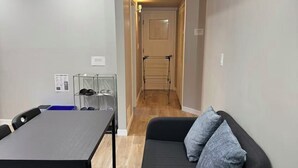 Una sala de estar moderna con un sofá negro, una mesa de comedor y un aparador de vidrio transparente.