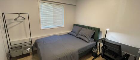 A bedroom with a bed, a desk, and a chair.