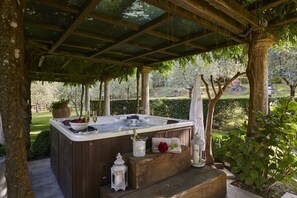 A hot tub under a wooden pergola with a garden view, surrounded by trees and greenery. - Villa Rigomagno By MMega (Rigomagno)