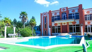 A pool area with a two-story building featuring arched windows and decorative patterns. - Premier Villas (Baku)