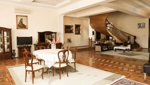 A spacious living room with a dining area, a staircase, and a large wooden table. - Premier Villas (Baku)