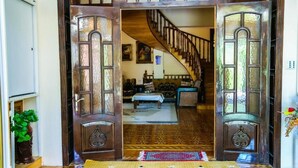 A wooden door with intricate carvings, leading to a room with patterned flooring and a staircase. - Premier Villas (Baku)