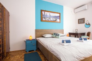 A bedroom with a wooden bed, a blue nightstand, a desk, and a chair.