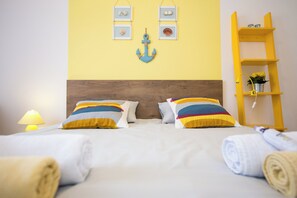 A neatly made bed with colorful pillows, a wooden headboard, and a yellow shelf with decorative items.