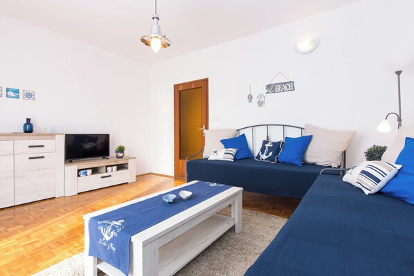 A modern living room with a sofa set, a television, and a small table with a blue cloth.