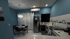 A compact kitchen with a refrigerator, sink, and dining area.