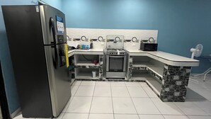 A compact kitchen with a refrigerator, stove, microwave, and a sink.