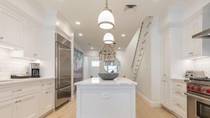 Una cocina moderna con armarios blancos, electrodomésticos de acero inoxidable y una isla central con un lavabo.
