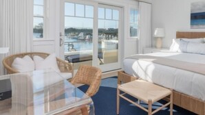 Habitación de hotel con cama, una mesita de cristal, una silla y vistas a una piscina y edificios.